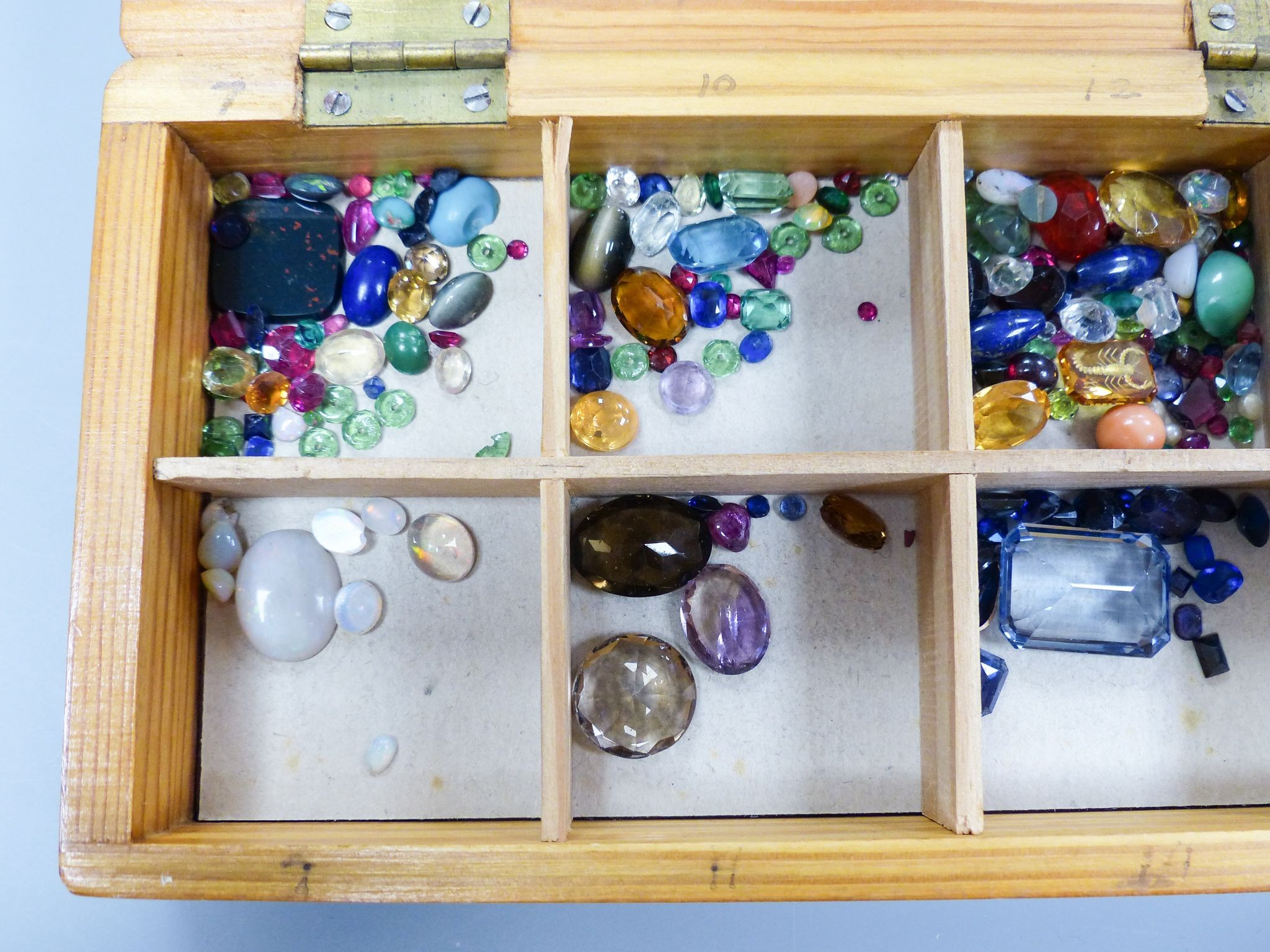 A quantity of unmounted gemstones, housed in a wooden box, including opal, opal doublet, bloodstone, turquoise, amethyst, rock crystal etc.